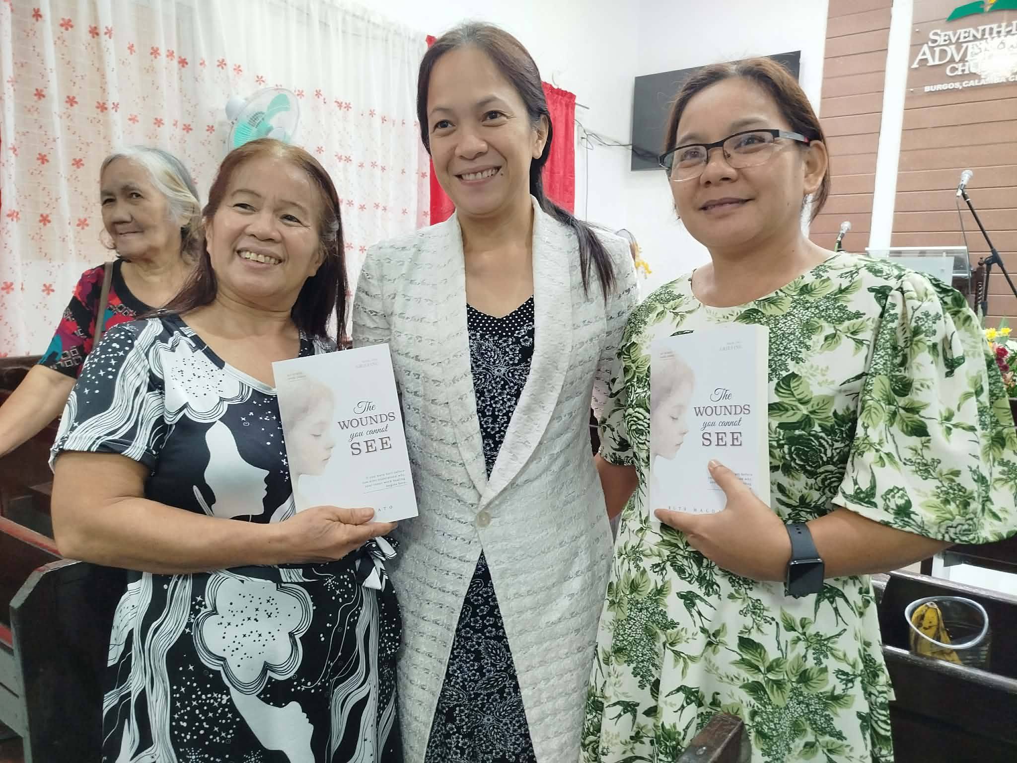 Community members holding copies of The Wounds You Cannot See